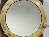 miroir en forme de hublot en laiton, présenté sur un socle en velours marron