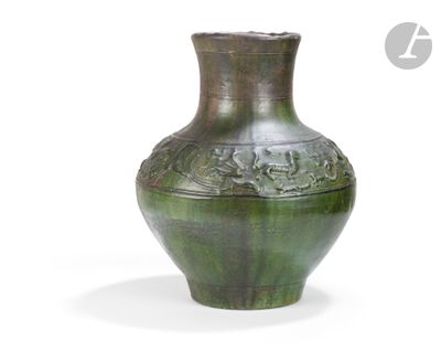 un vase vert posé sur une surface blanche