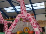 une grande girafe gonflable au milieu d'une aire de jeux