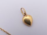a close up of a gold heart pendant on a gold chain