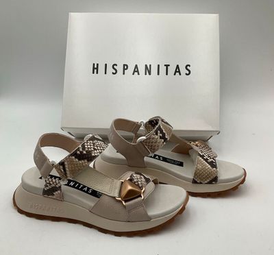 Les chaussures sont de couleur beige et blanche, avec un nœud doré sur le bout.
