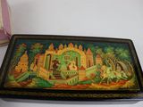 a small box with a painting on it next to a book