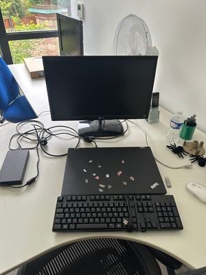 a desk with a computer, keyboard, mouse, and other items on it