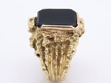 a close up of a gold ring with a black stone