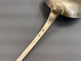 a silver spoon with a handle on a gray surface