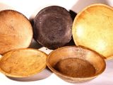 several wooden bowls are arranged in a circle on a white surface