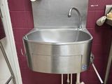 a stainless steel sink in the corner of a bathroom