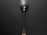 a silver spoon with a metal handle on a black surface