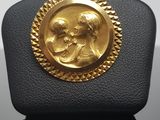 a close up of a gold plated brooch with a woman and child
