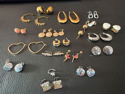 many pairs of earrings on a black surface