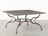 une table en fer avec un plateau en béton et des pieds en fer