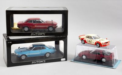 trois petites voitures sont exposées dans une vitrine posée sur une surface blanche