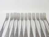 six forks are lined up in a row on a white surface