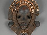 an image of a wooden mask with shells on its head