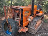 un tracteur orange garé sur la terre battue