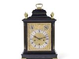 une horloge noire et or posée sur une surface blanche