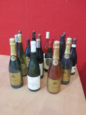 Des bouteilles de vin sont alignées sur une table devant un mur rouge