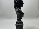 a black sculpture of a woman ' s head on a pedestal