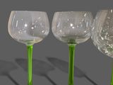 four green wine glasses sitting on top of each other on a table