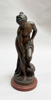bronze statue of a woman kneeling on a rock with her hands on her knees