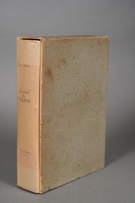 an old book sitting on top of a table next to a cup