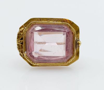 a close up of a pink stone ring on a white surface