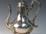 a silver tea pot on a stand on a table