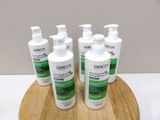 six flacons de gel hydroalcoolique Dercosol posés sur un plateau en bois