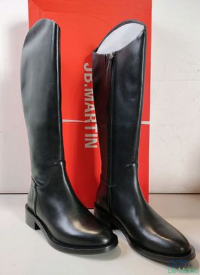 Les bottes noires se trouvent à côté d'une boîte rouge sur la table.