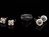three pairs of earrings and a ring on a black surface