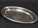 an oval silver plate with a handle on a black background