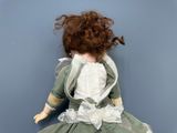 a doll that is wearing a green dress and a white dress