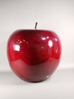 une pomme rouge posée sur une surface blanche