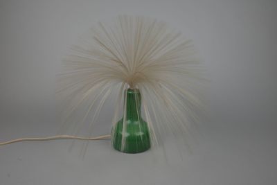 un vase vert dans lequel se trouve une plume blanche