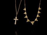 two gold necklaces and a cross on a black background