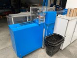 a blue machine that is sitting next to a trash can