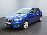 Une voiture bleue est garée dans une pièce au sol noir.