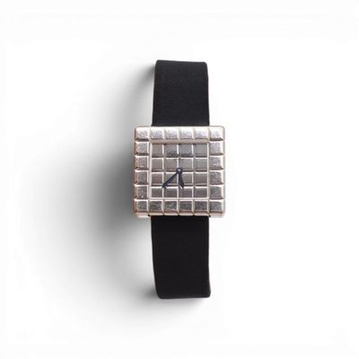 une photo d'une montre carrée argentée avec un bracelet noir
