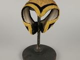 masque jaune et noir posé sur un support, sur fond blanc