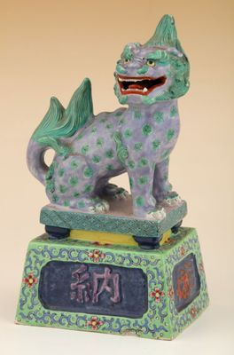 figurine chinoise représentant un chien violet et vert sur un socle vert