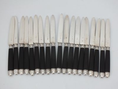 six silver and black handled knives are lined up on a white surface