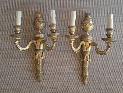 two antique brass wall sconces with candles on them