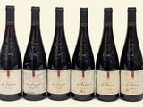 six bottles of wine are lined up in a row on a white surface