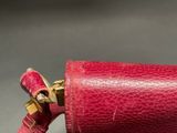 a red purse with a gold handle on a gray surface