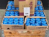 plusieurs cartons de canettes de soda bleu posés sur une palette en bois
