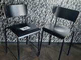 two black chairs sitting next to each other in front of a wall