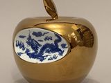 une pomme dorée sur laquelle est représenté un dragon bleu