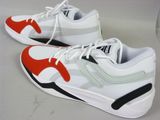 une paire de baskets blanches rehaussées de touches rouges et noires, posée sur une table