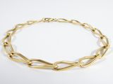 gros plan d'un bracelet en chaîne en or sur une surface blanche