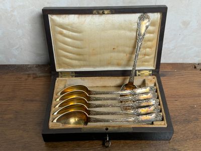 des couverts dans un coffret posé sur une table en bois, avec un mur en arrière-plan